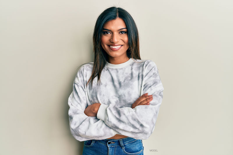 Smiling transgender woman standing with her arms crossed.